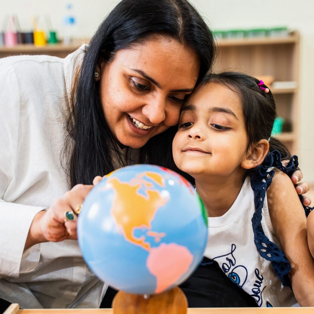 A Della Junior teacher and a little girl exploring a world globe together