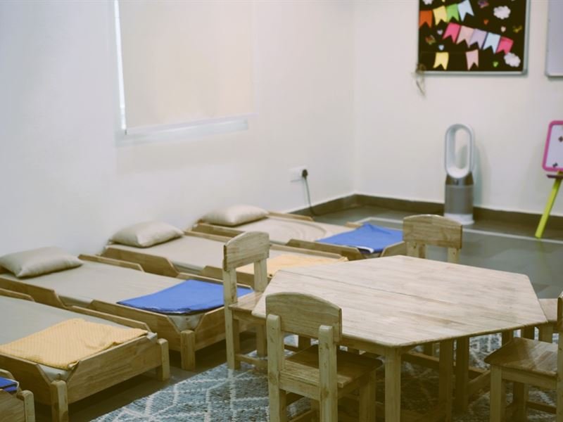 The daycare room with little beds and a play table