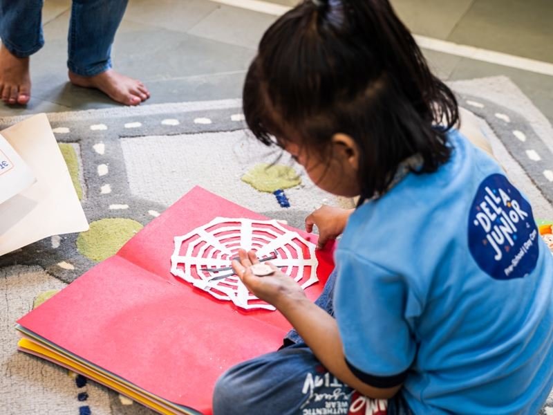 A girl making a paper spider-web craft