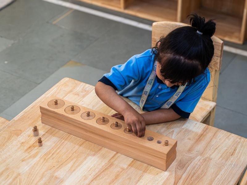 A girl fitting wooden cylinders into a block