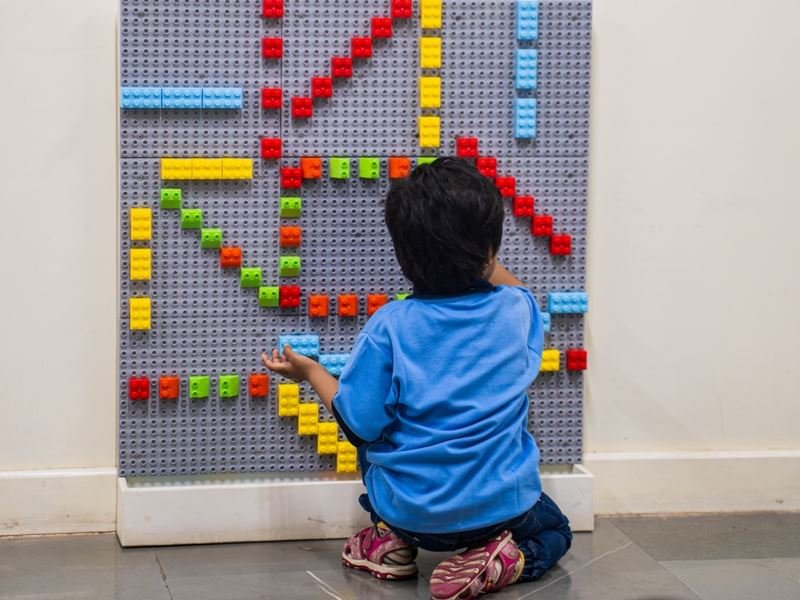A child building patterns on a Lego wall