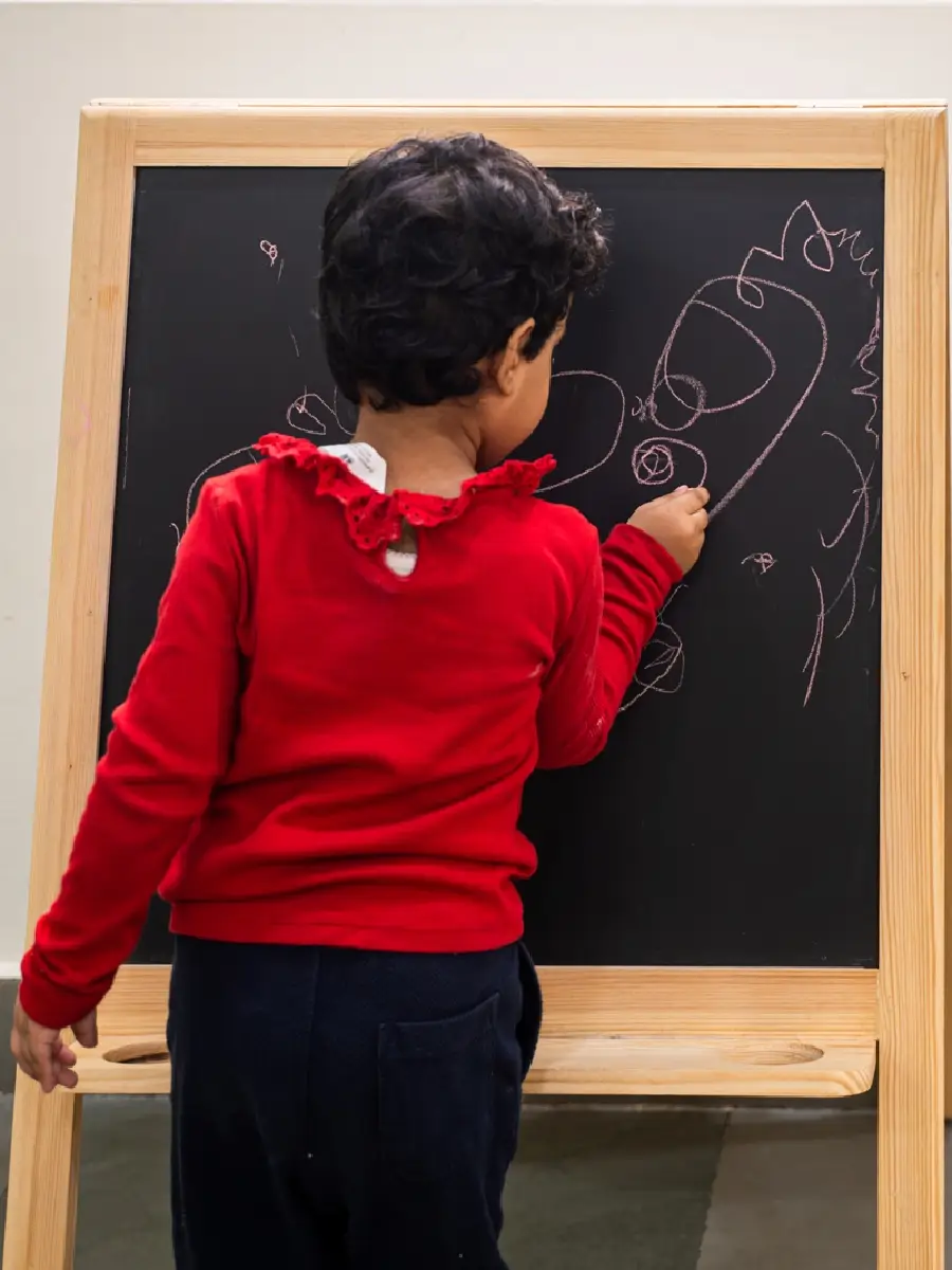 A child drawing with chalk on a blackboard easel