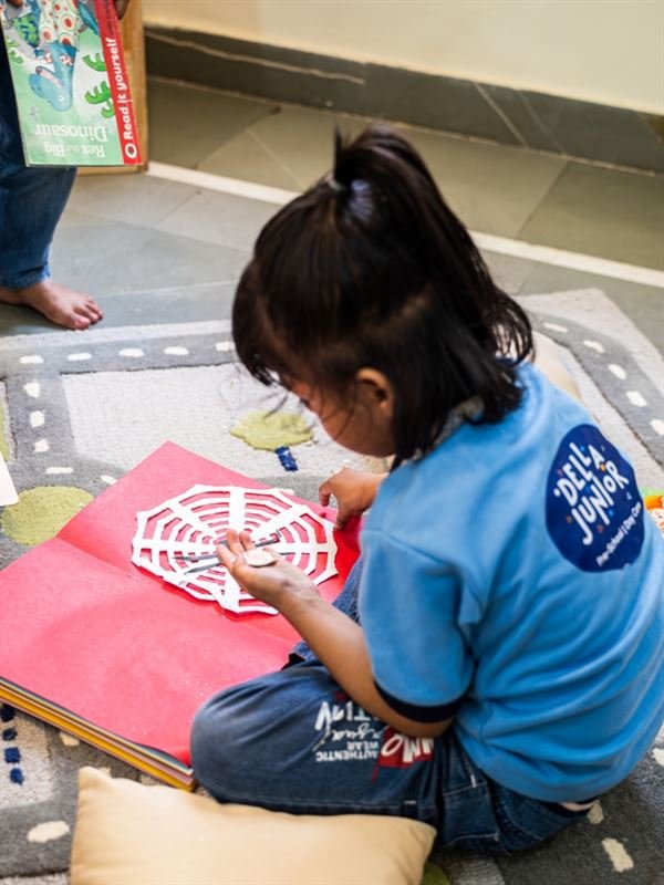 A girl making a paper spider-web craft