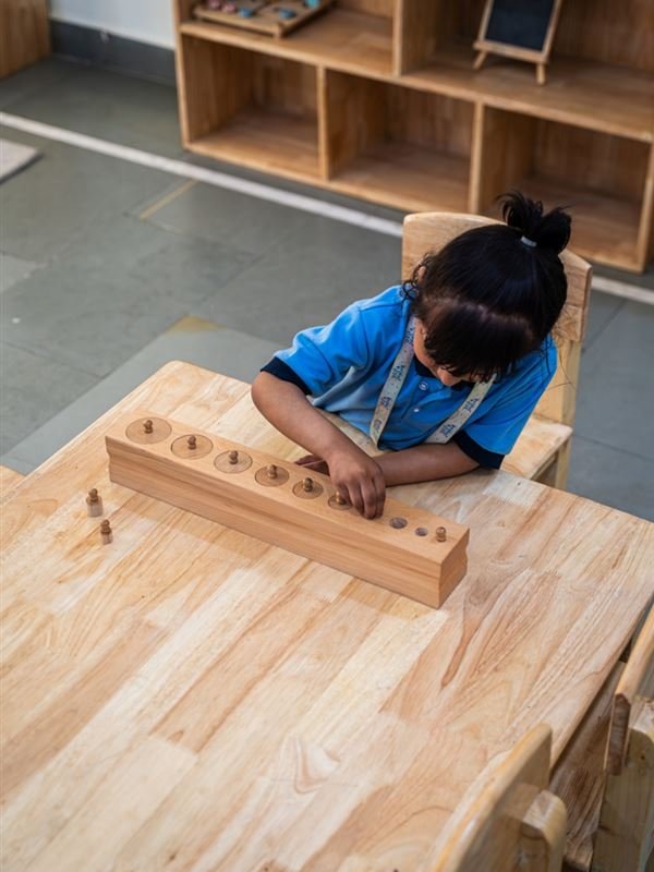 A girl fitting wooden cylinders into a block