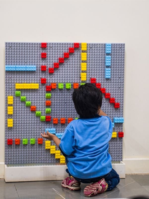 A child building patterns on a Lego wall