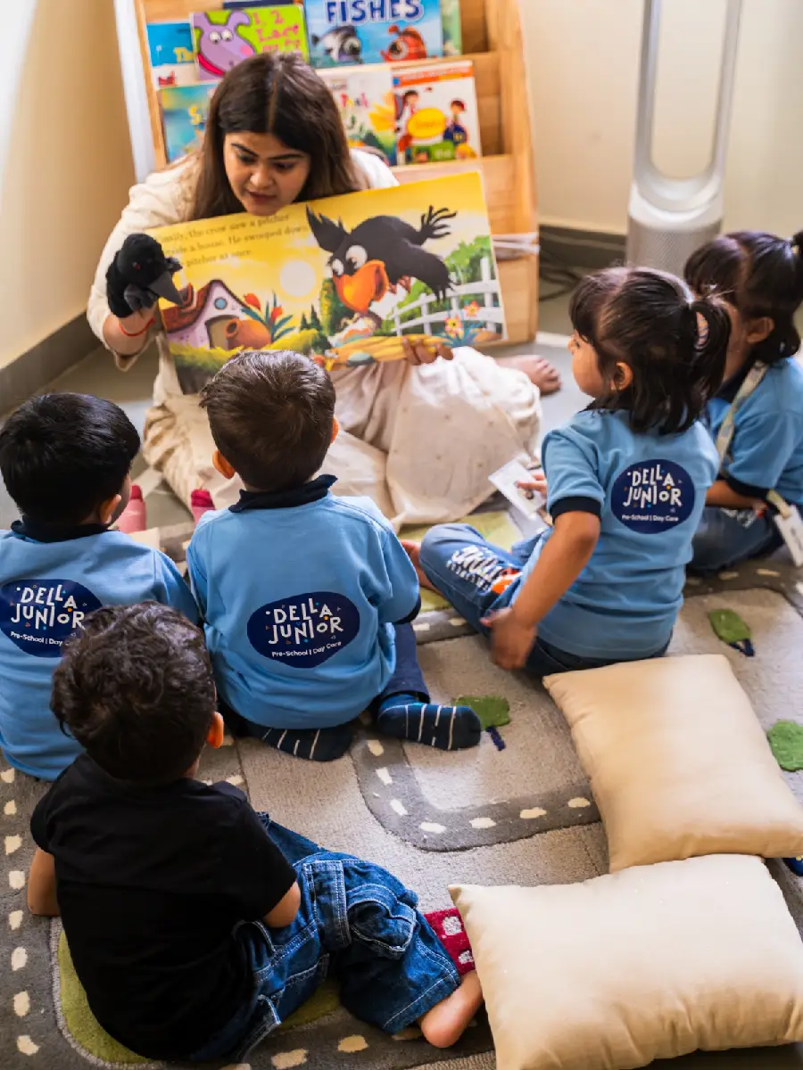 A teacher reading a picture book to children with a puppet